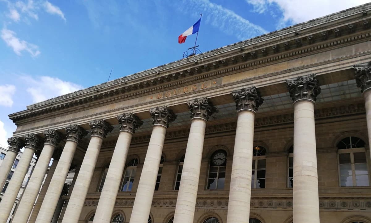 French flag flying above the historic Palais Brongniart building in Paris.