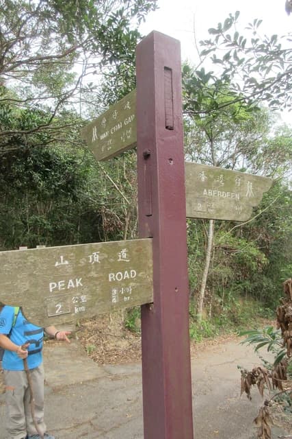 Wooden signpost in Hong Kong trail pointing towards Wan Chai Gap, Peak Road, and Aberdeen.
