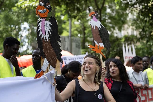 A woman smiles and holds a cardboard cutout of a bird during a housing rights demonstration.