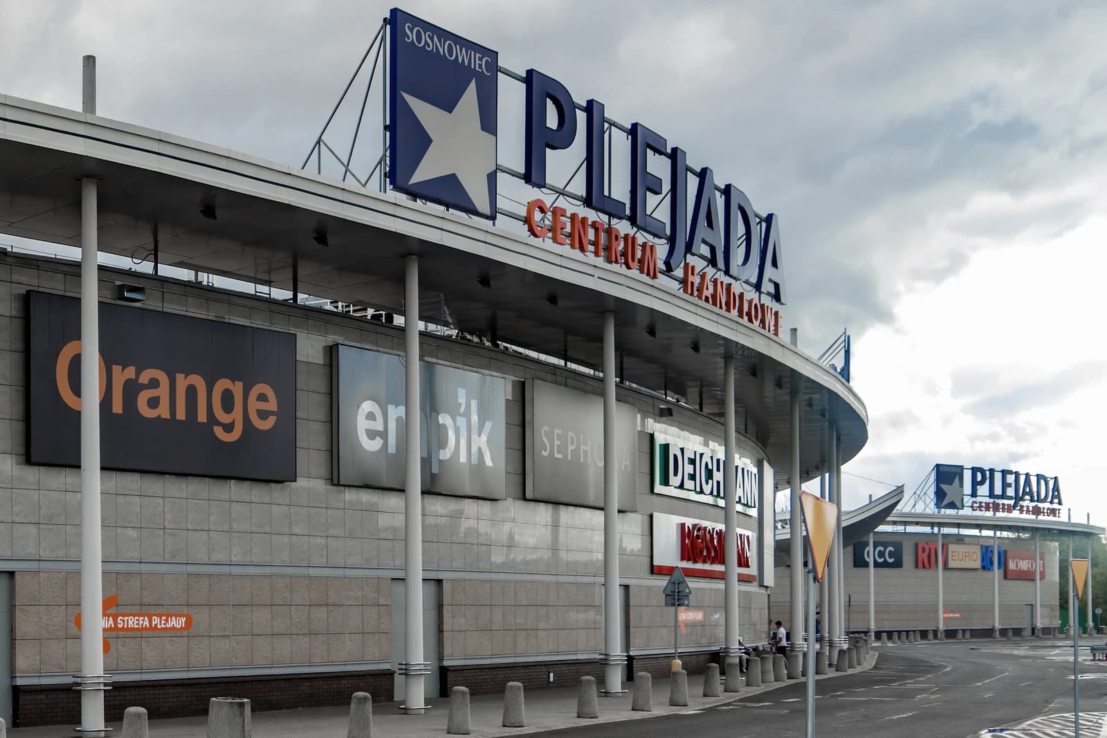 Exterior of the Plejada shopping center in Sosnowiec, Poland, under a cloudy sky.