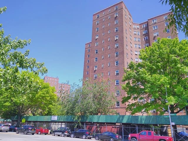 Patterson Houses brick apartment buildings with green trees and parked cars along the street.