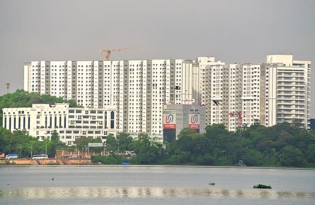 Skyscrapers and buildings under construction in Powai, Mumbai, viewed across a body of water.