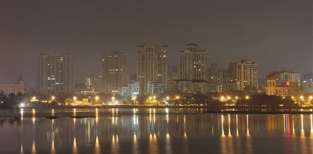 Night view of residential and commercial buildings in Hiranandani Gardens, Powai, illuminated at night.