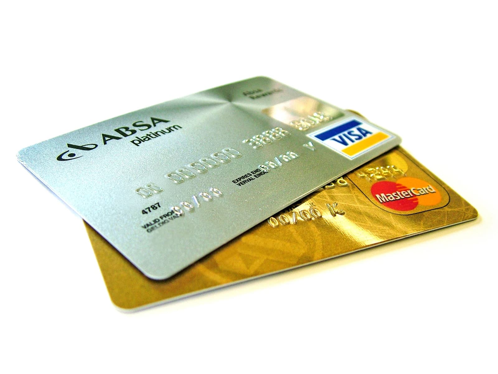 Two credit cards, an ABSA Platinum Visa and a Mastercard, lying on a white surface.