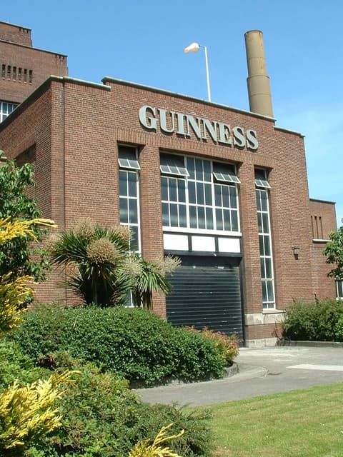 Front view of a brick brewery building with 'GUINNESS' signage on the facade.