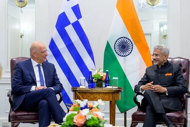 S. Jaishankar and Nikos Dendias sit across from each other with national flags behind them.