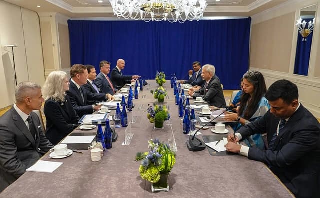 A large group of officials seated around a long conference table during a meeting.