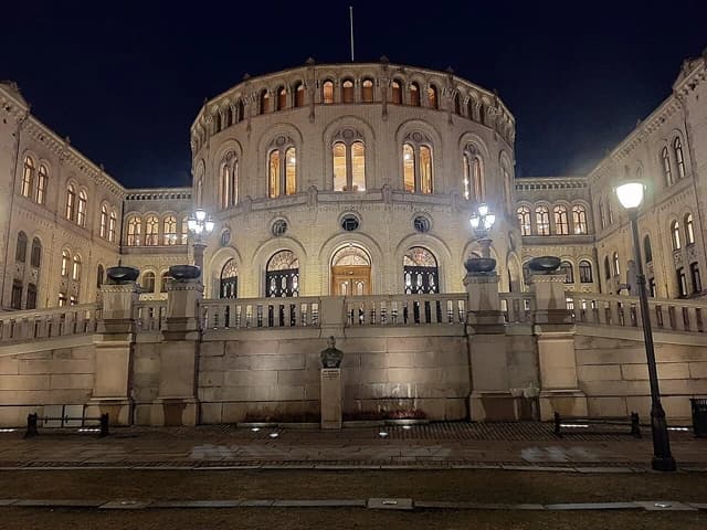 The illuminated Storting building in Oslo, Norway, at night, viewed from the front.