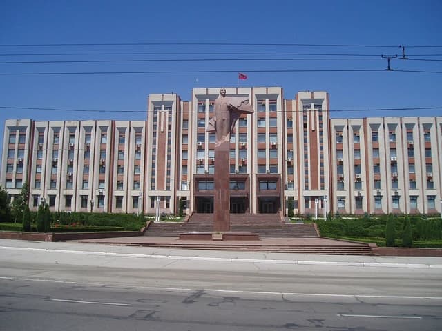 Supreme Soviet building in Tiraspol, Transnistria, with a large statue of Lenin in front.