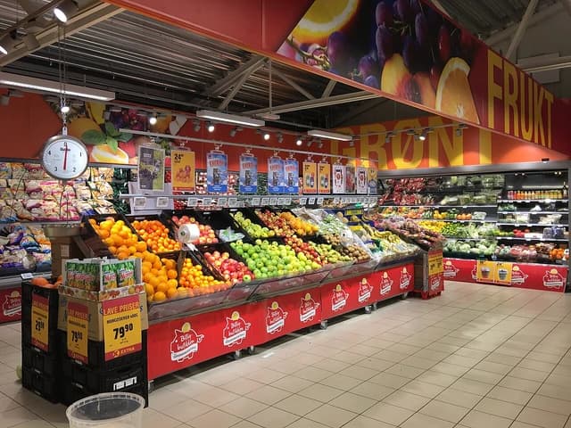 Interior of a supermarket with a wide selection of fresh fruits and vegetables on display.
