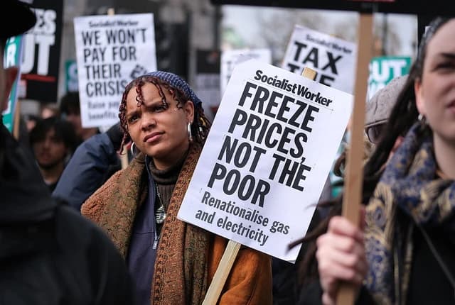 Woman holding a protest sign during a demonstration against rising prices.