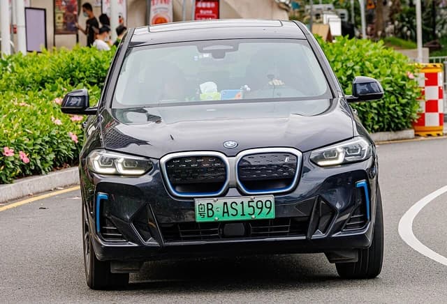 Dark blue BMW iX3 (G08) electric SUV driving on a street in China.