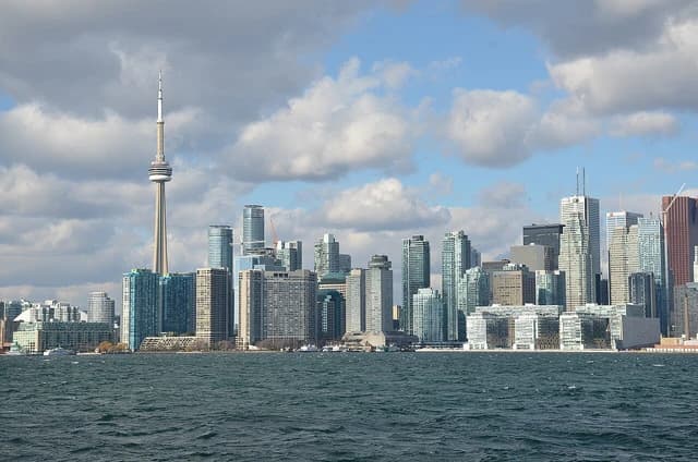 Toronto skyline with CN Tower visible from across the water under a partly cloudy sky.