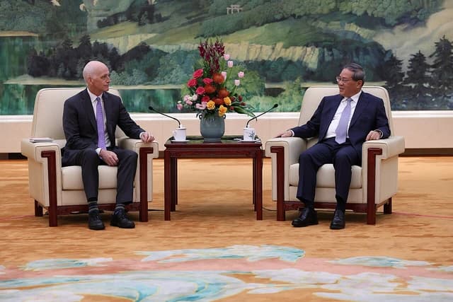 US Representative Adam Smith and Chinese Premier Li Qiang sitting in chairs facing each other.