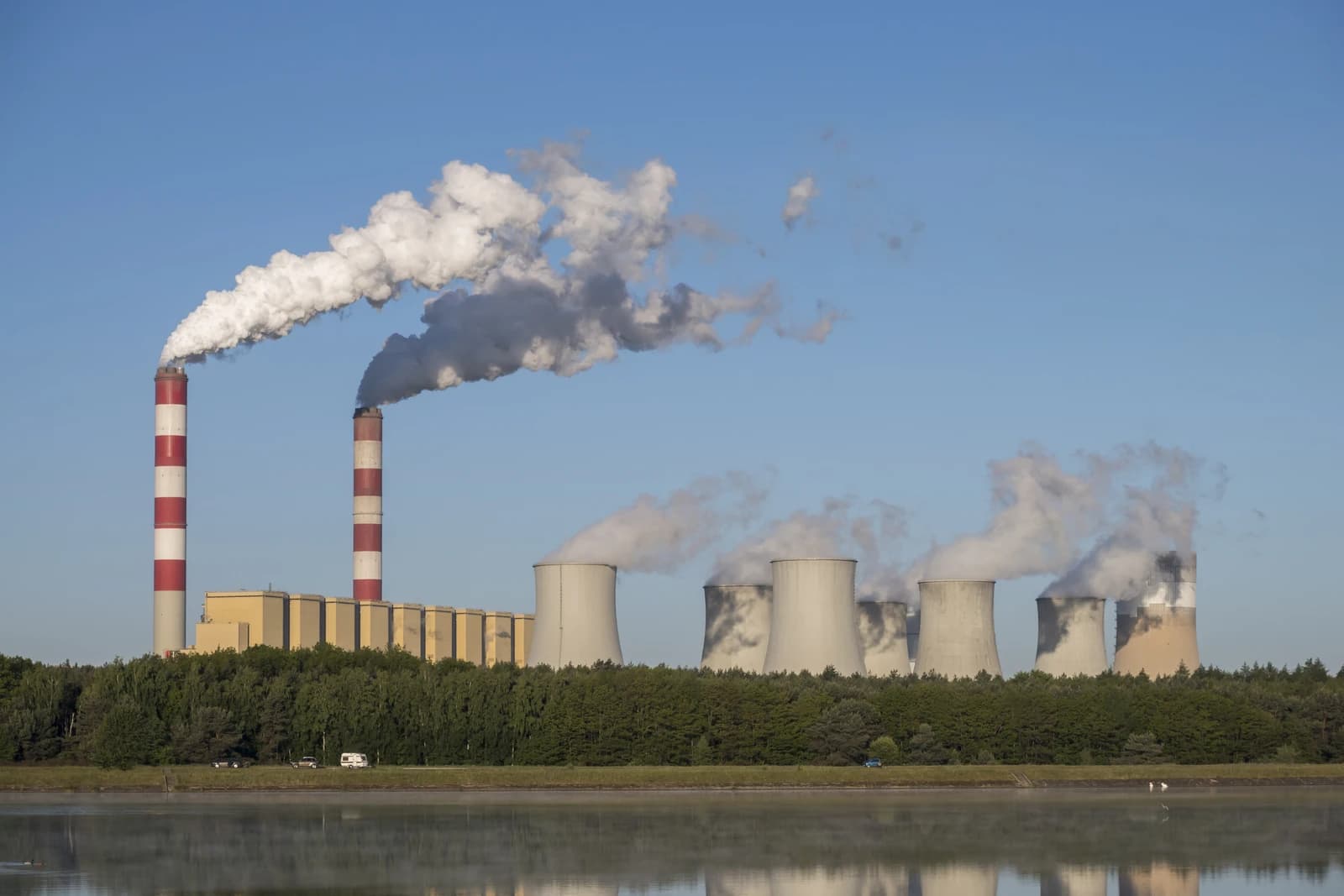 Smoke plumes rise from striped chimneys and cooling towers at the Belchatow power plant.