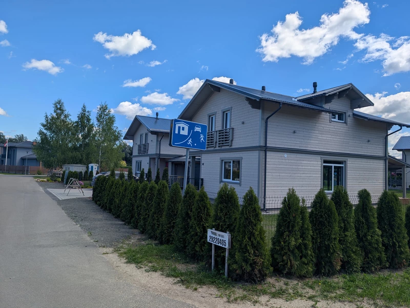 Residential building with light siding and dark roof, seen from a street perspective.
