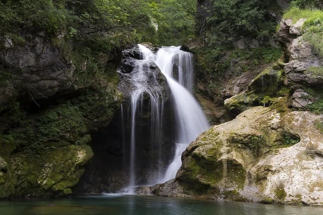 Waterfall cascading over rocks into a clear pool within Vintgar Gorge, Slovenia.