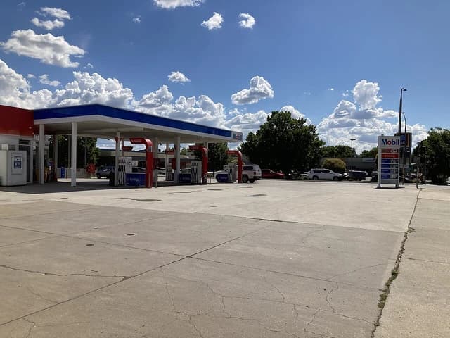 A Mobil gas station with pumps and signage under a clear blue sky.