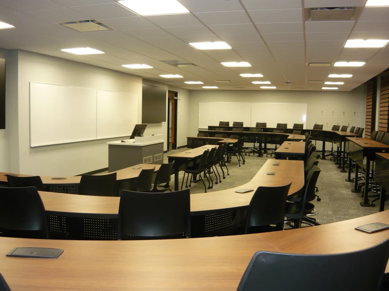 An empty classroom with semicircular desks, chairs, and whiteboards at the Edwards School of Business.