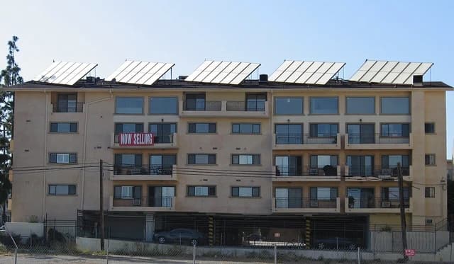 An apartment building featuring numerous solar panels mounted on its roof.