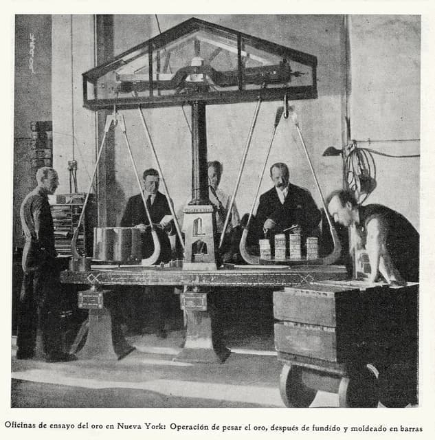 Men weigh gold bars on a large scale inside a New York assay office.