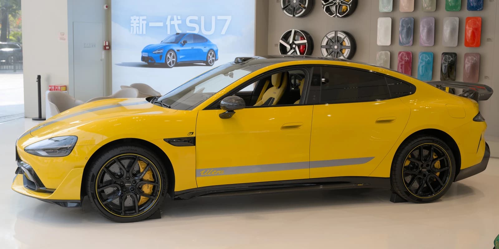 Yellow Xiaomi SU7 Ultra electric car in a showroom, side view.