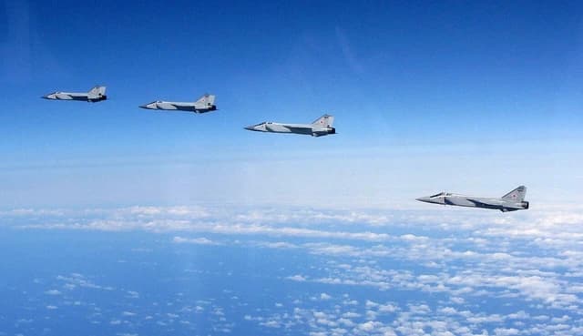 Four Russian military fighter jets flying in formation over clouds.