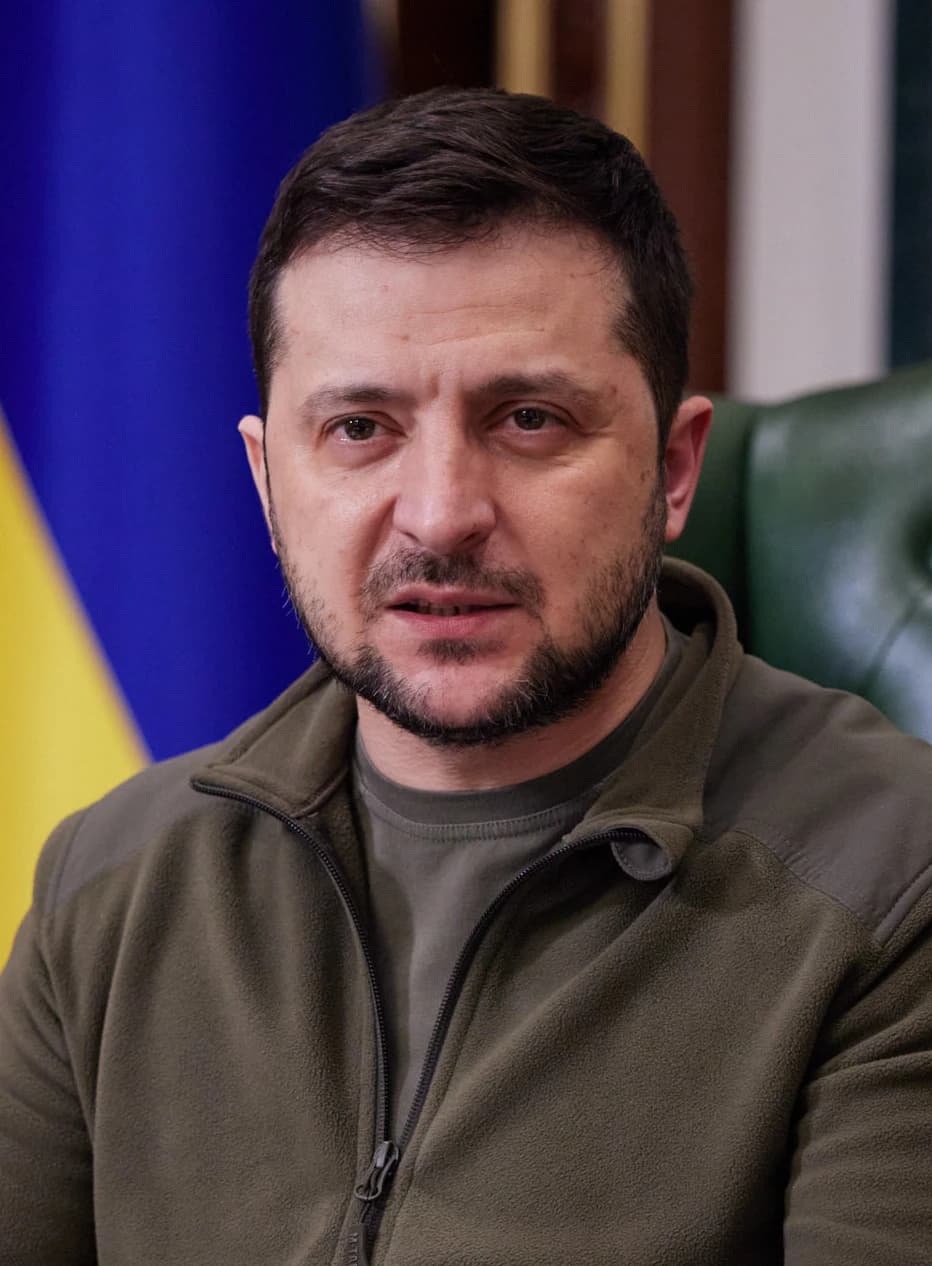 Ukrainian President Volodymyr Zelenskyy speaks during an address, with a Ukrainian flag in the background.