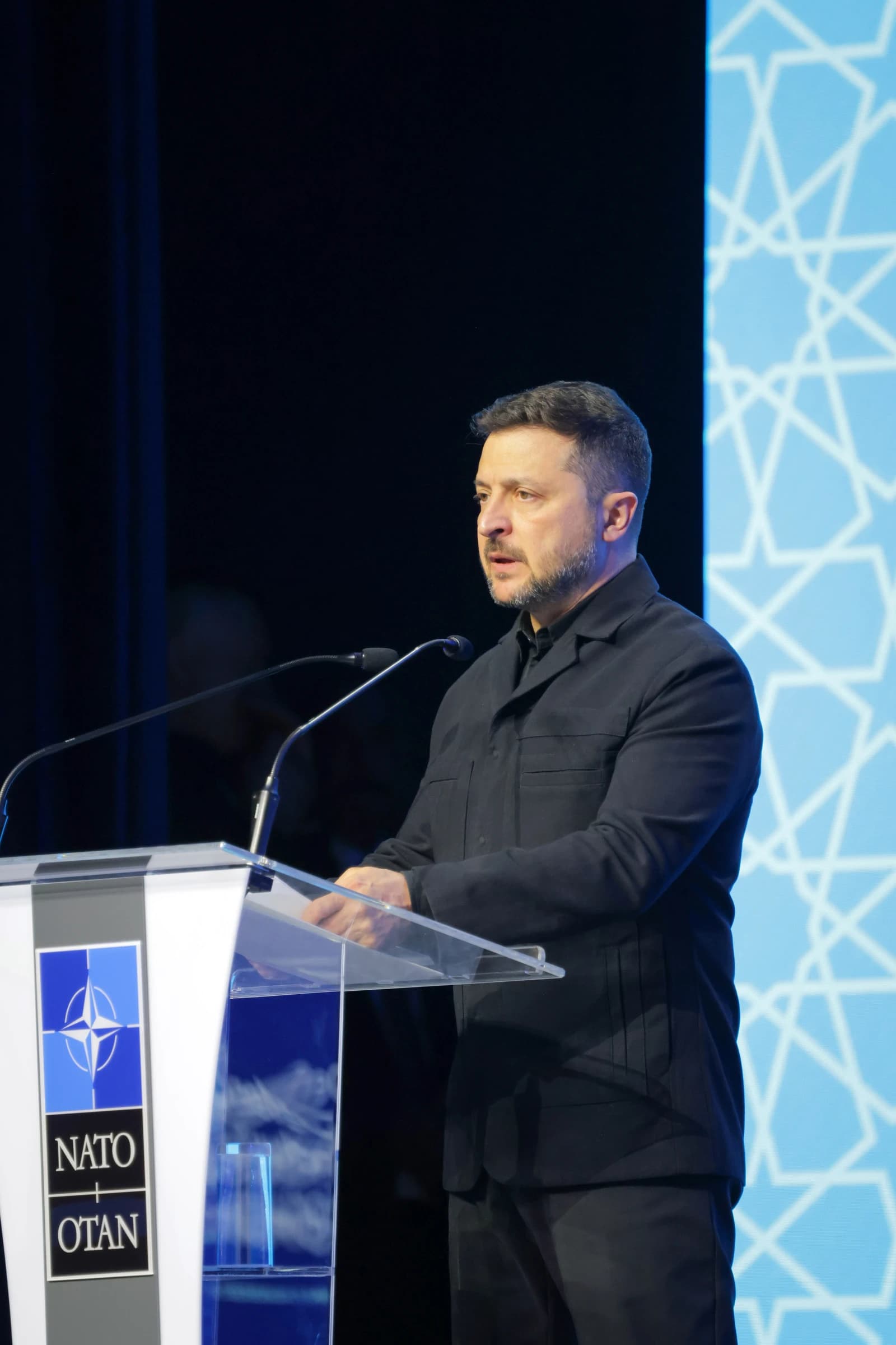Volodymyr Zelenskyy, President of Ukraine, speaking from a podium at a conference.