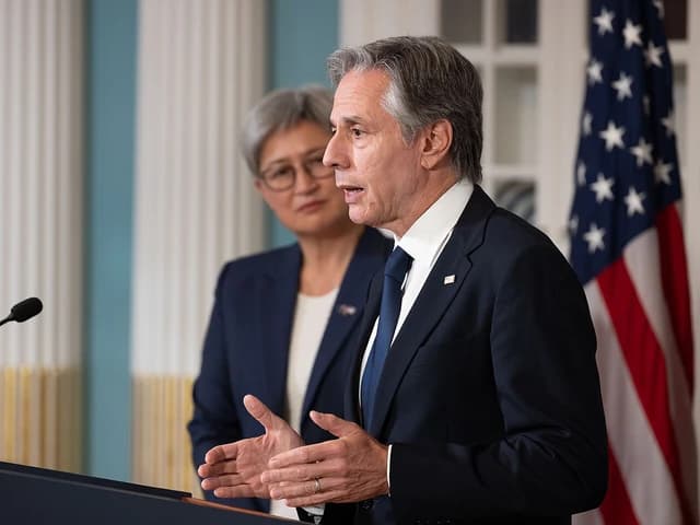 U.S. Secretary of State Antony Blinken speaking at a podium with Australian Foreign Minister Penny Wong behind him.