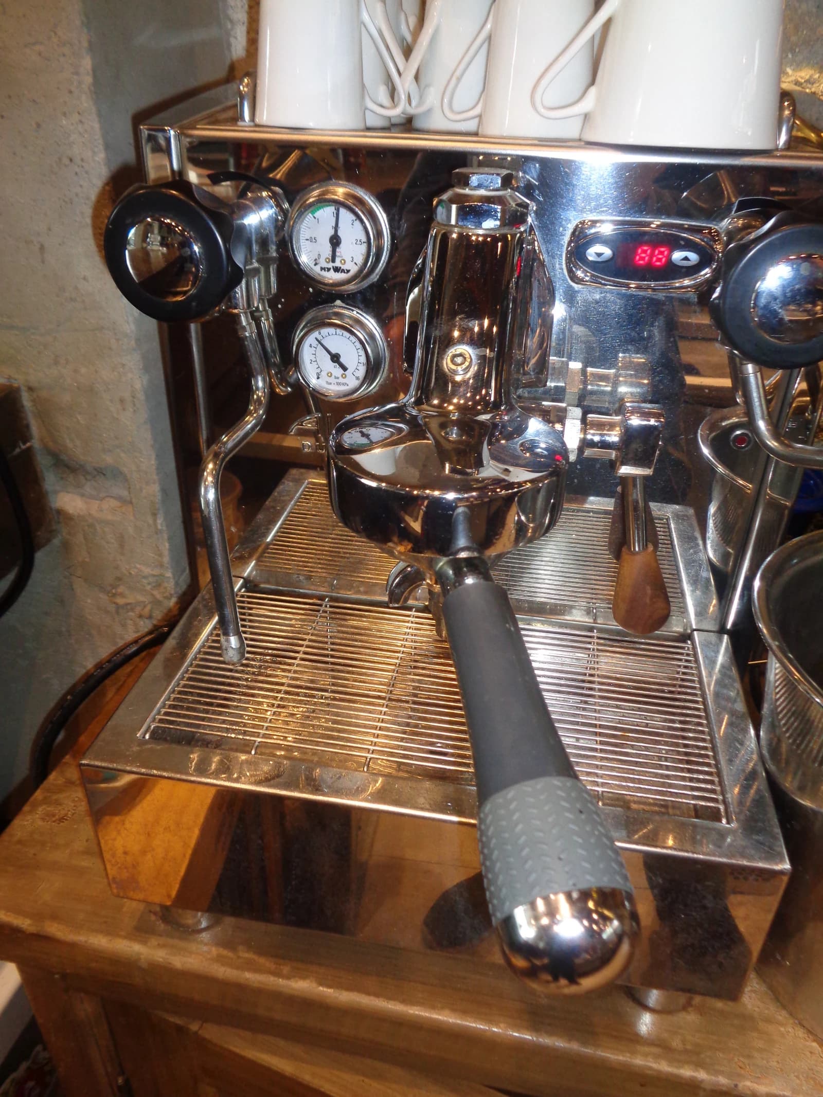 Close-up view of a professional espresso machine on a wooden counter.