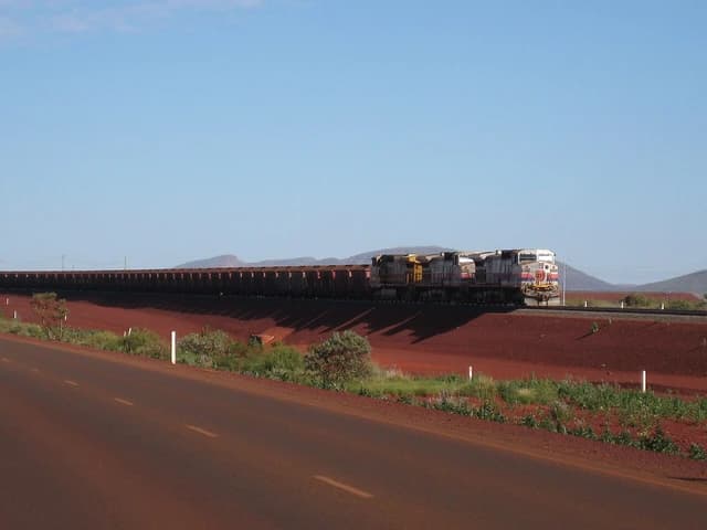An iron ore train traveling through a red earth landscape.