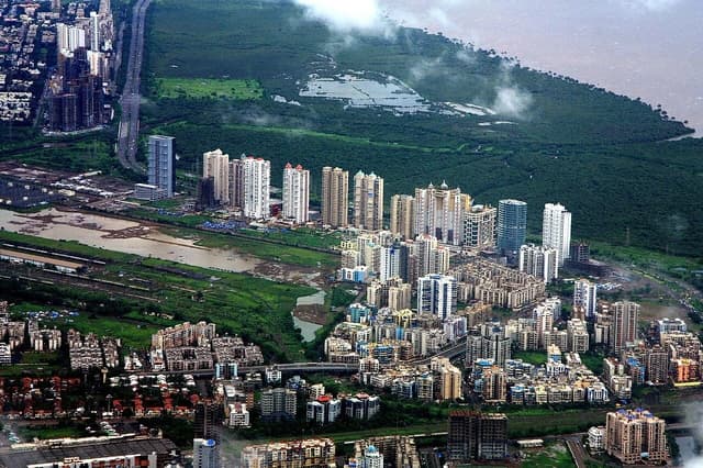 Aerial view showing residential and commercial buildings in Navi Mumbai, India, with green landscape.