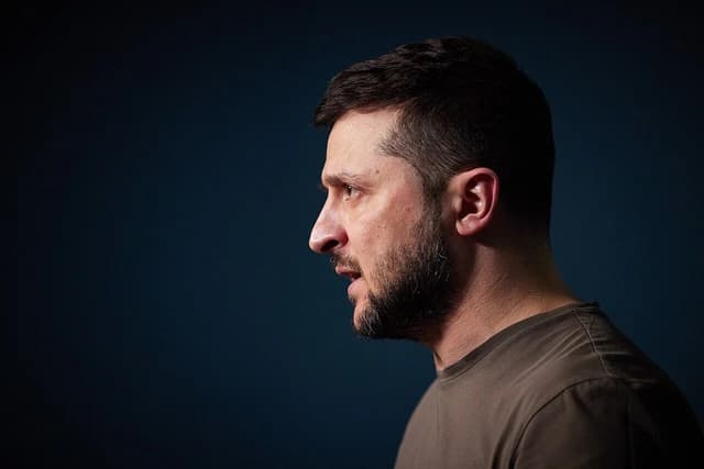 Volodymyr Zelenskyy, President of Ukraine, speaking in profile against a dark background.