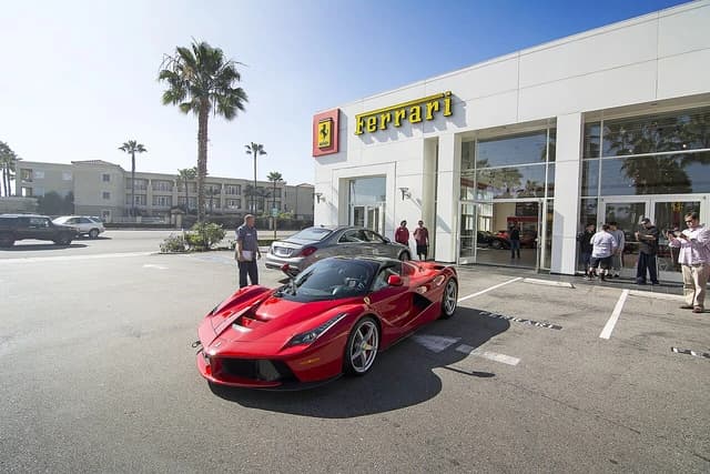 Red LaFerrari sports car parked in front of a white Ferrari dealership building.