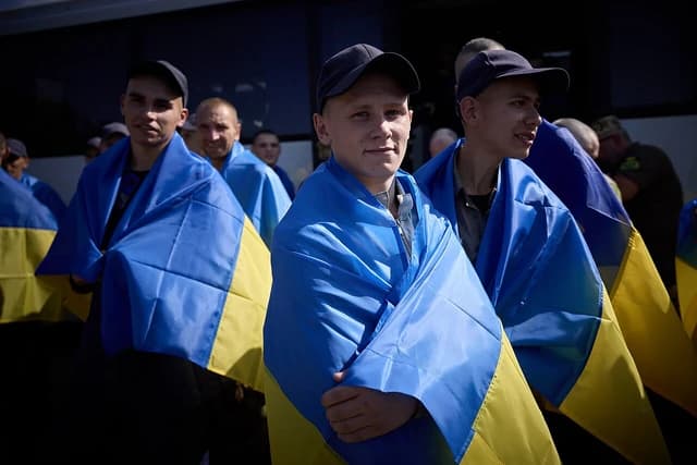 Ukrainian soldiers wrapped in Ukrainian flags after a prisoner exchange.