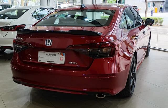 Rear view of a red Honda Civic e:HEV hybrid car parked inside a showroom.