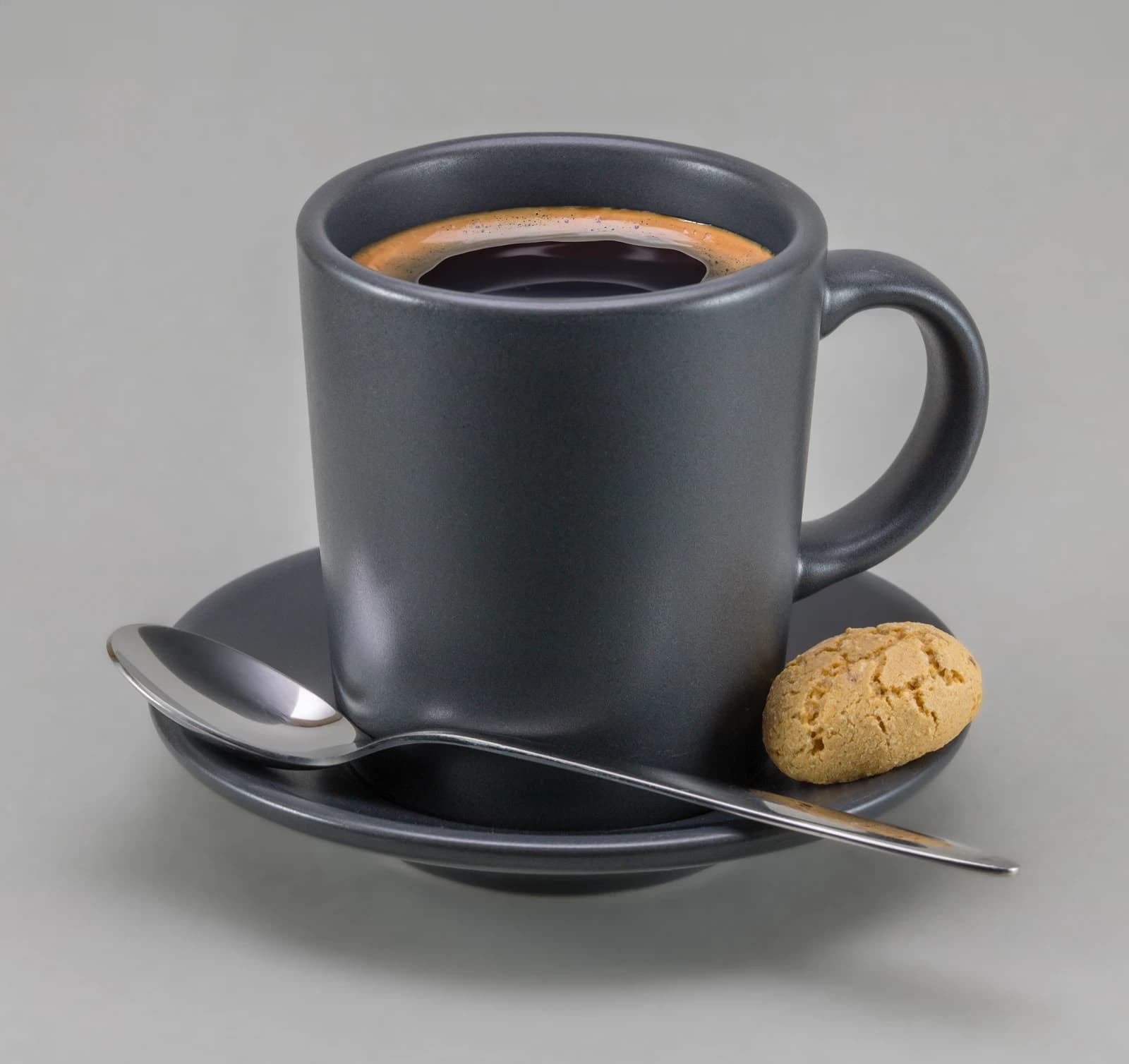 Gray espresso cup on saucer with a spoon and an amaretto cookie.