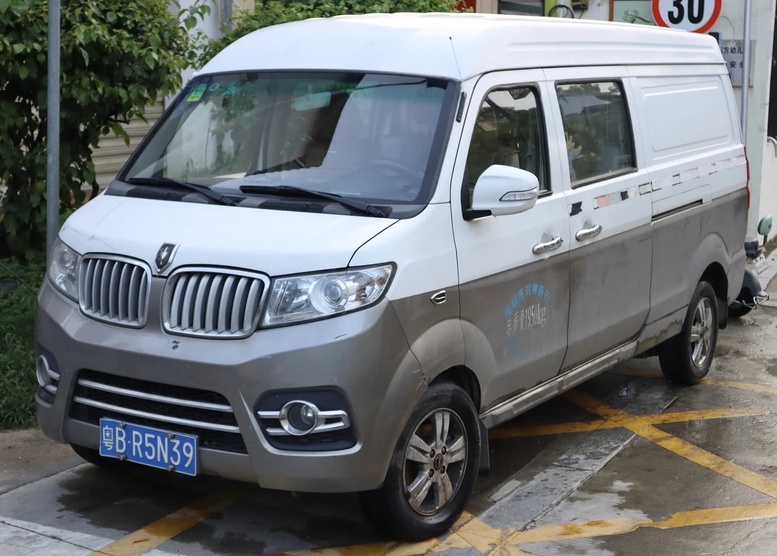 White and grey Brilliance Jinbei New Haise X30L van parked on a street.