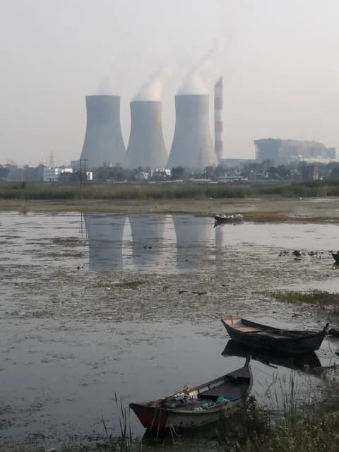 Three cooling towers of a thermal power plant emitting steam near Nagpur, Maharashtra, India.