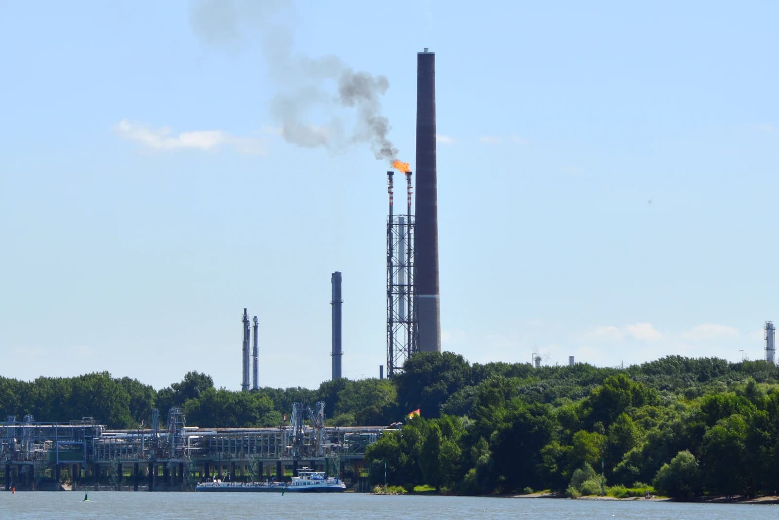 Gas flare burning atop a tall stack at a chemical plant.