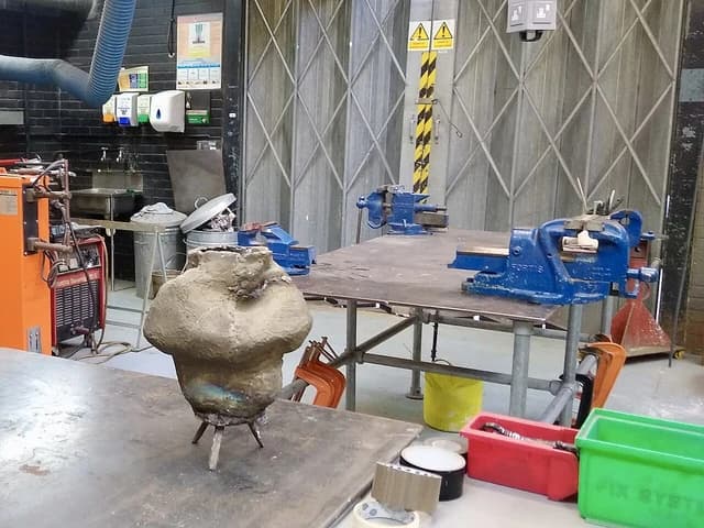Metalwork workshop at University for the Creative Arts, with vises, welding equipment, and a metal sculpture.