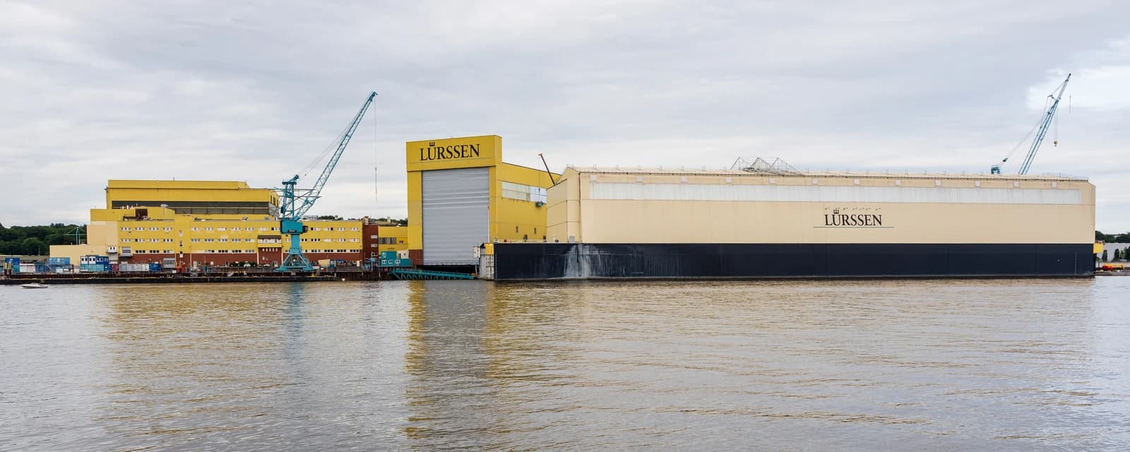 Lürssen-Werft shipyard buildings and a partially visible ship on the water in Bremen-Vegesack.