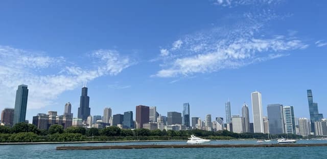 Chicago Loop skyline with skyscrapers and boats on Lake Michigan under a blue sky.