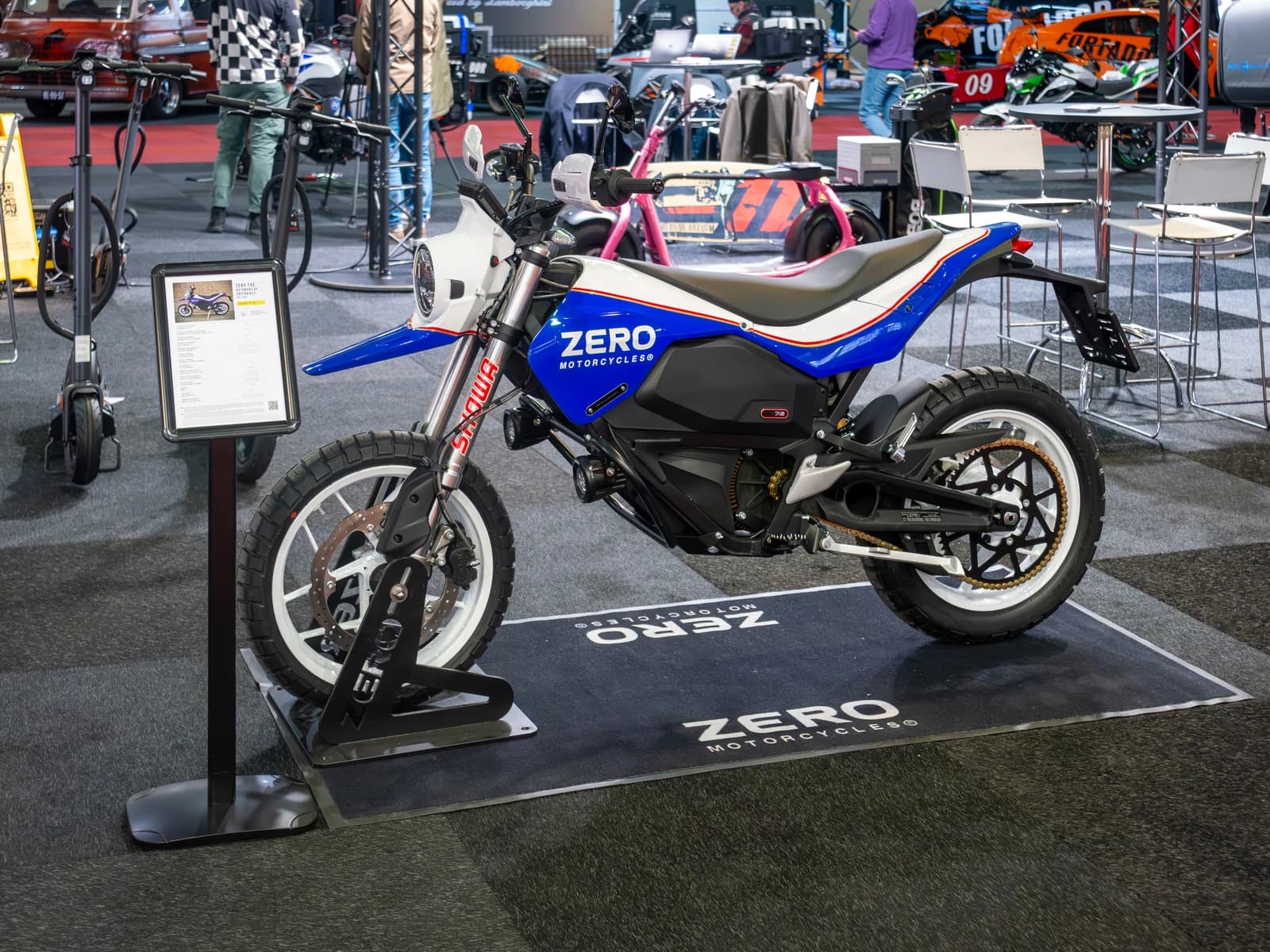 A blue and white Zero Motorcycles electric motorcycle on display at an exhibition.