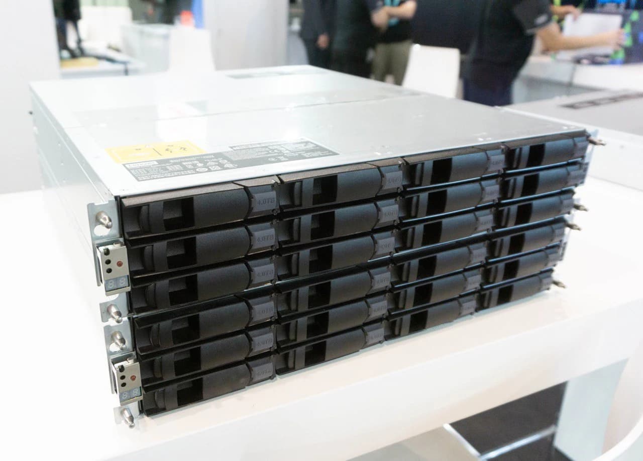 Several rows of black hard drive bays in a silver server rack system.