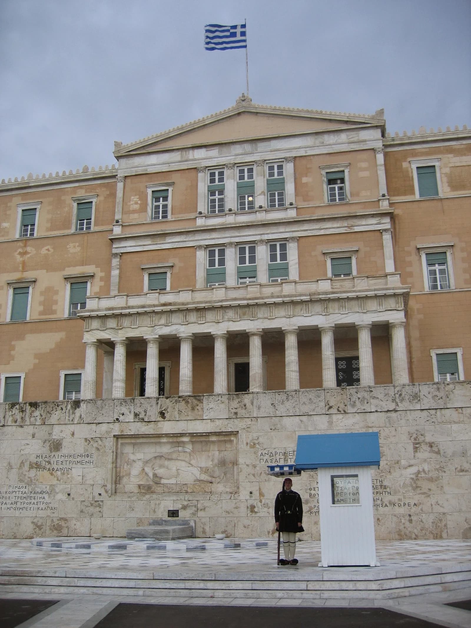 Exterior of the Hellenic Parliament building in Athens, Greece, under a grey sky.