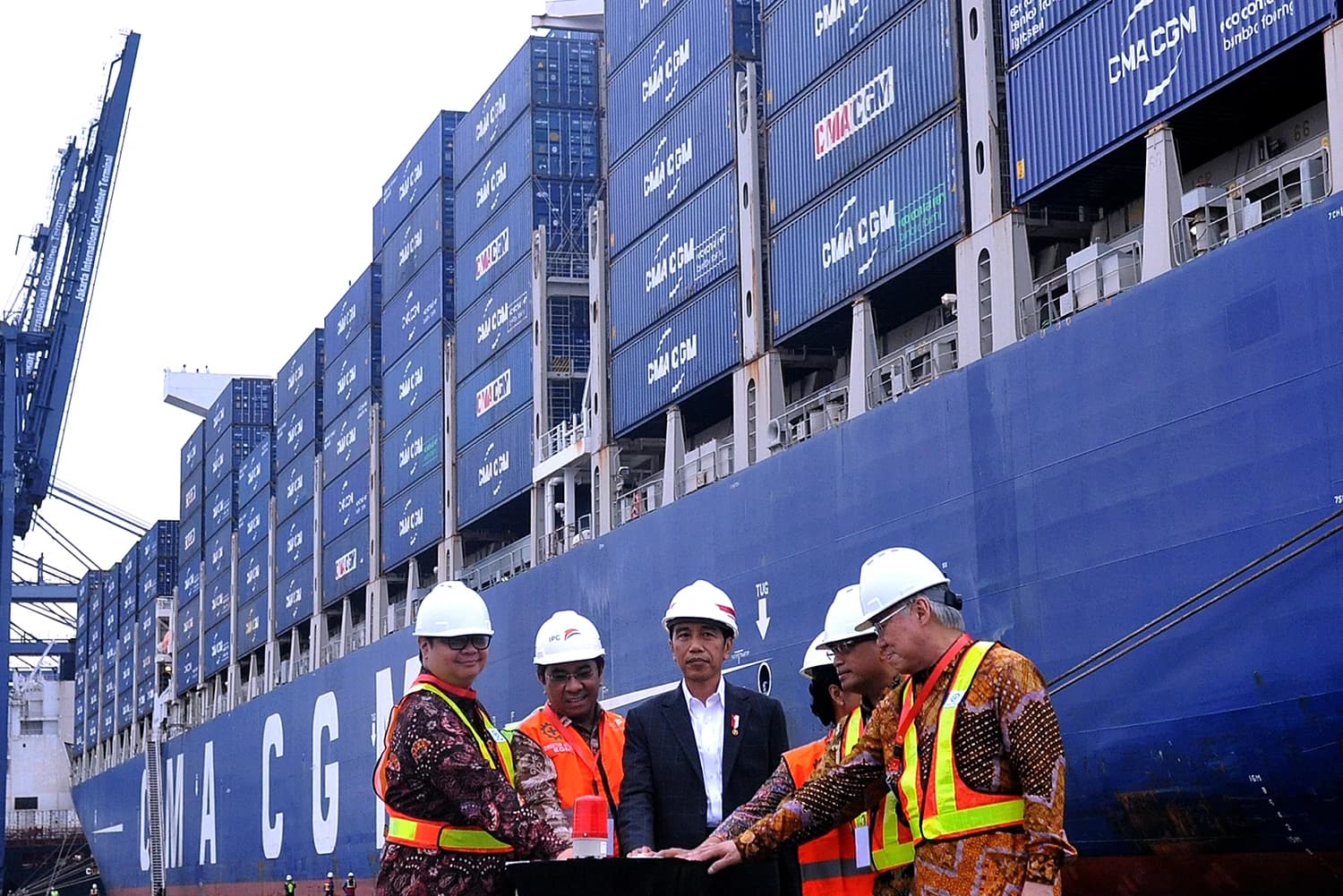 President Joko Widodo and several officials in hard hats and vests at a port.