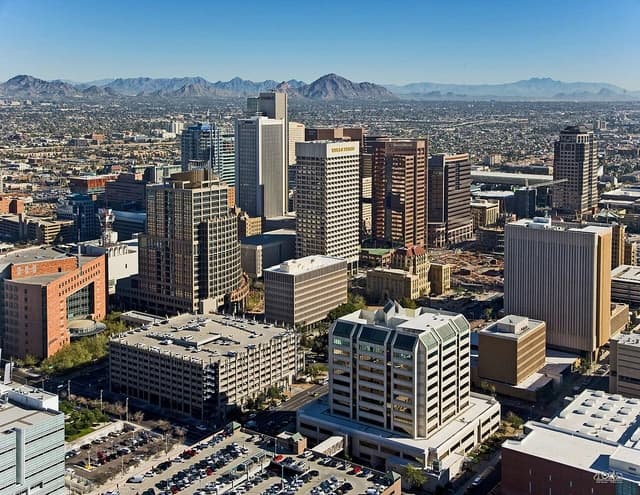 Aerial view showing multiple high-rise buildings in downtown Phoenix under a clear sky.