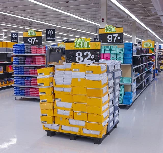 Walmart store aisle with a large display of school notebooks and 'Back to School' signs.